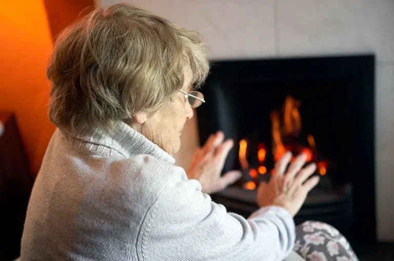Woman Warming Hands By Fire At Home